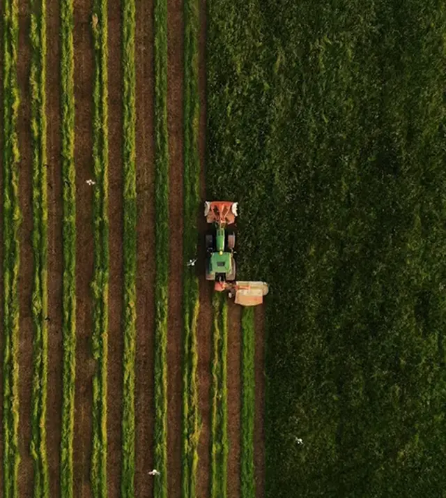 Трактор обрабатывает поле, вид с верху